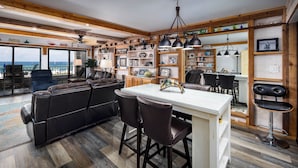 Una cocina moderna con una isla central, taburetes de bar y vistas al océano.