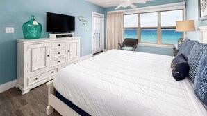 A bedroom with a bed, a television, a dresser, and a view of the ocean. - Emerald Towers West 4000 - Ocean Kissed (Fort Walton Beach)