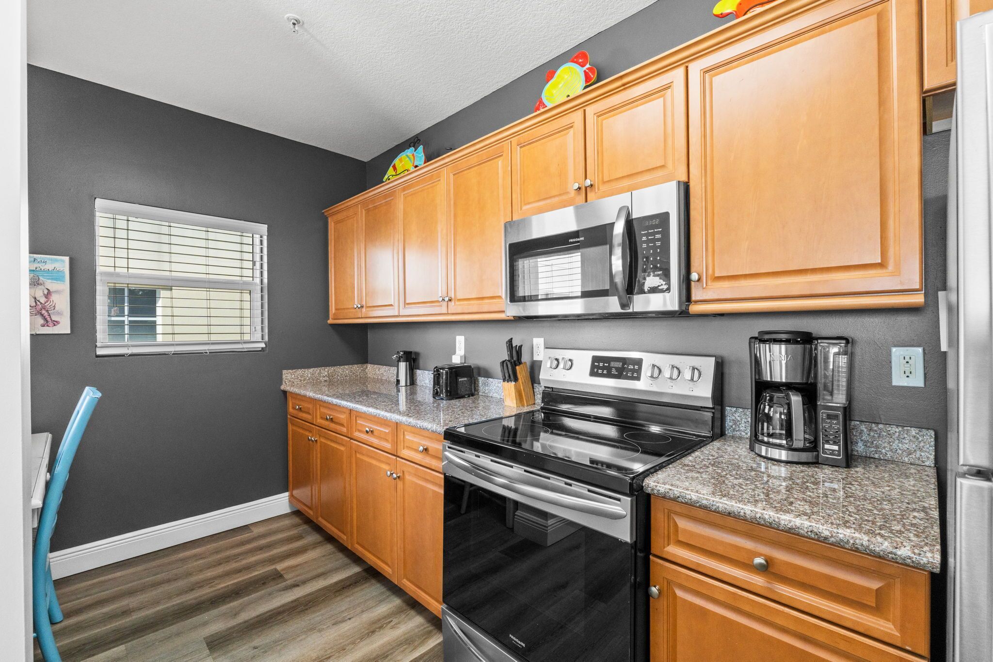 A kitchen with wooden cabinets, a stainless steel microwave, a black stove, and a granite countertop.