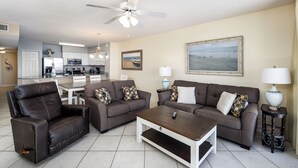 A living room with a sofa, armchair, coffee table, and a dining area with a table and chairs. - Island Princess 701 - Beach Bum Bliss (Fort Walton Beach)