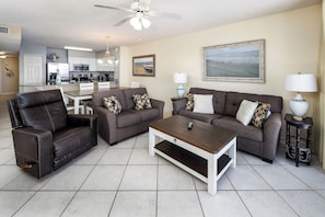 A living room with a sofa, armchair, coffee table, and a dining area with a table and chairs. - Island Princess 701 - Beach Bum Bliss (Fort Walton Beach)