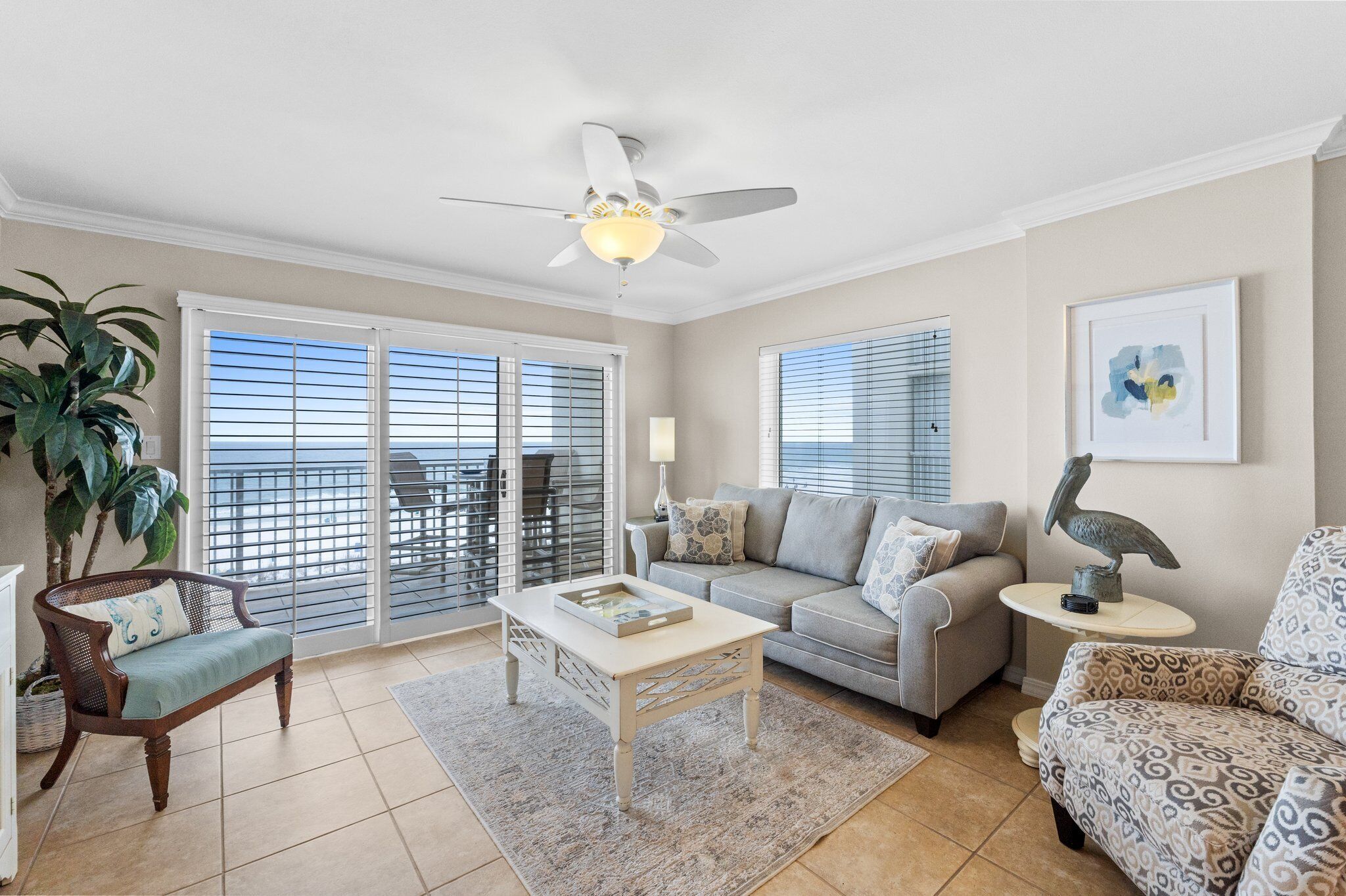 A living room with a ceiling fan, a sofa, a patterned armchair, and a coffee table.