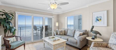 A living room with a ceiling fan, a sofa, a patterned armchair, and a coffee table.
