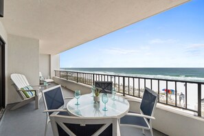 A balcony with a table, chairs, and a view of the beach. - Surf Dweller 406 - The Beachcomber (Fort Walton Beach)