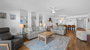 Een moderne woonkamer met een bank, salontafel en een eethoek met stoelen en een tafel.