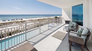 A balcony with a view of the beach, a pool, and seating area with a table and chairs. - Blu 306 - The Gulf Jewel (Fort Walton Beach)