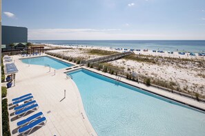 A pool area with lounge chairs and a view of the beach. - Blu 306 - The Gulf Jewel (Fort Walton Beach)