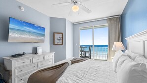 Une chambre d’hôtel dotée d’un grand lit, d’un téléviseur à écran plat, d’un ventilateur de plafond et offrant une vue sur l’océan depuis le balcon.