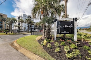 A sign for 'Dune Pointe' at 670 Santa Rosa Blvd, surrounded by a landscaped garden with palm trees and various plants. - Dune Pointe 402 - Shells, Surf & Sea Turtles (Fort Walton Beach)