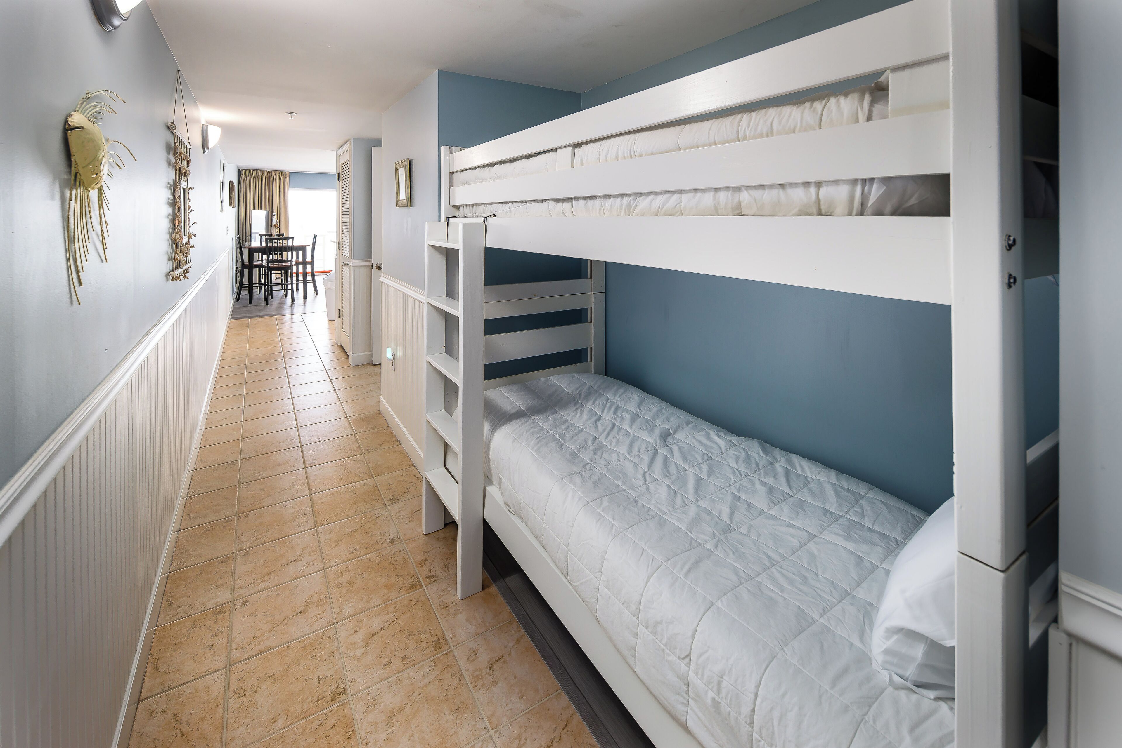 A bunk bed room with a tiled floor, a dining table with chairs, and a view to the dining area.