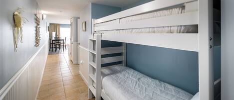 A bunk bed room with a tiled floor, a dining table with chairs, and a view to the dining area.