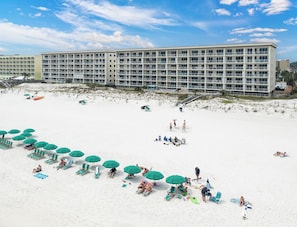 Ein Strandhotel mit mehreren Balkonen, Liegestühlen und Sonnenschirmen.