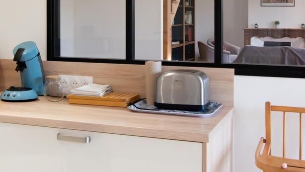 Eine Küchenzeile mit Kaffeemaschine, Toaster und einer Holzausziehtafel.
