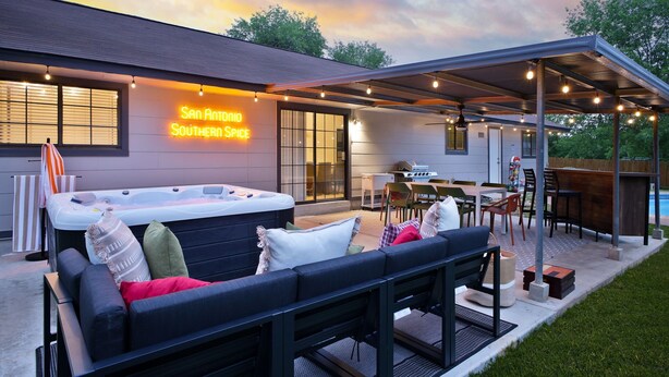 Un área de patio al aire libre con un jacuzzi, asientos y un letrero de neón que dice 'San Antonio Southern Spice'.