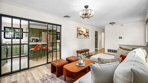 Un salón moderno con una mesa de centro de madera, un sofá gris y una araña.