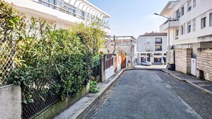A narrow urban street with buildings on both sides, a parked car, and a clear sky. - Appartement Proche Plage (Royan)
