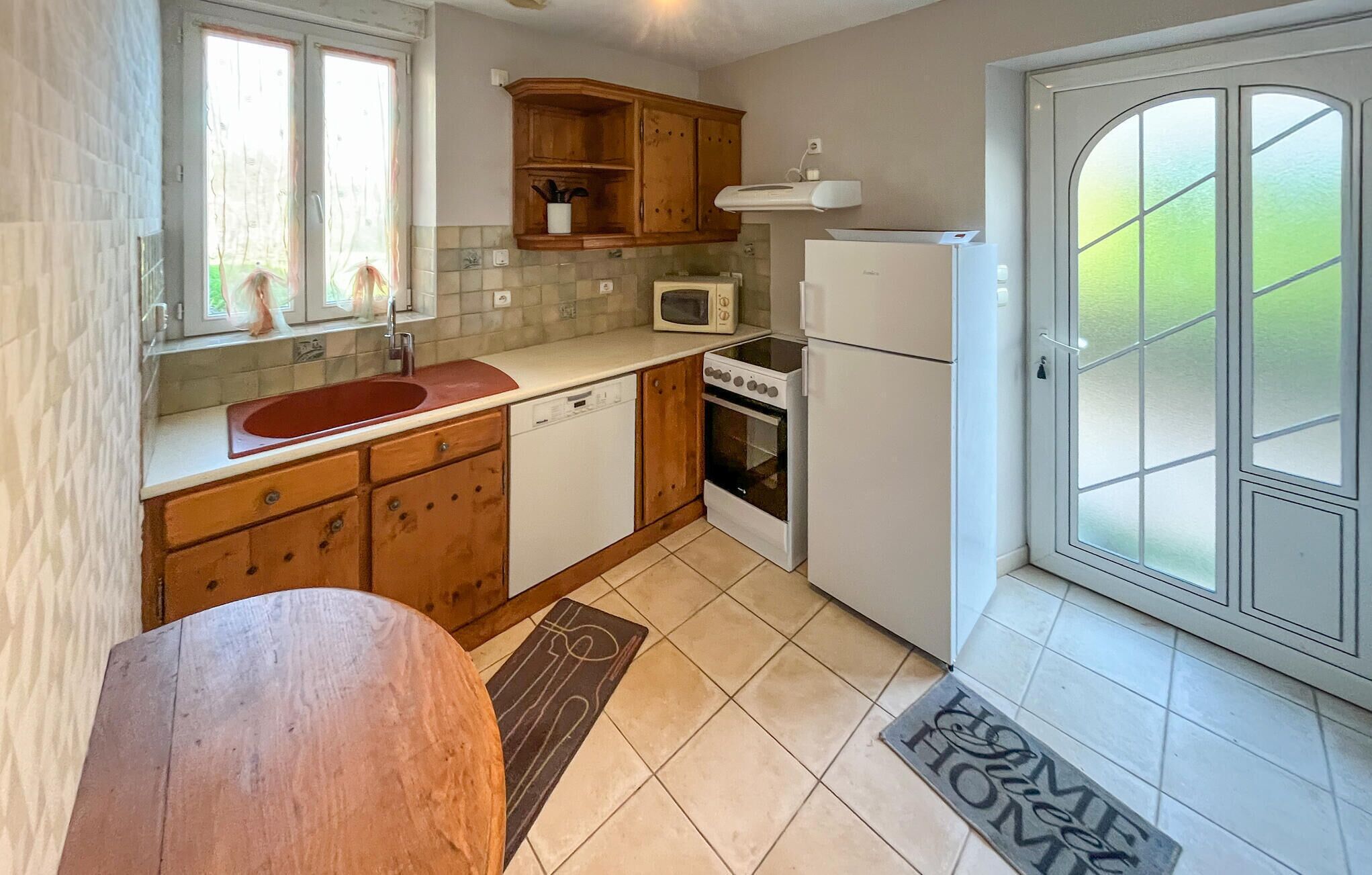 A compact kitchen with wooden cabinets, a microwave, a stove, and a refrigerator.
