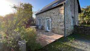 Ein Steinhaus mit einer Terrasse, zwei Türen und einem kleinen Tisch mit Stühlen.