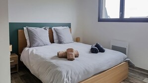 Una cama bien hecha con almohadas, un cabecero de madera y dos mesitas de noche con lámparas.