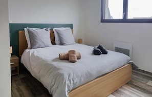 Ein ordentlich bezogenes Bett mit Kissen, einem hölzernen Kopfteil und zwei Nachttischen mit Lampen.