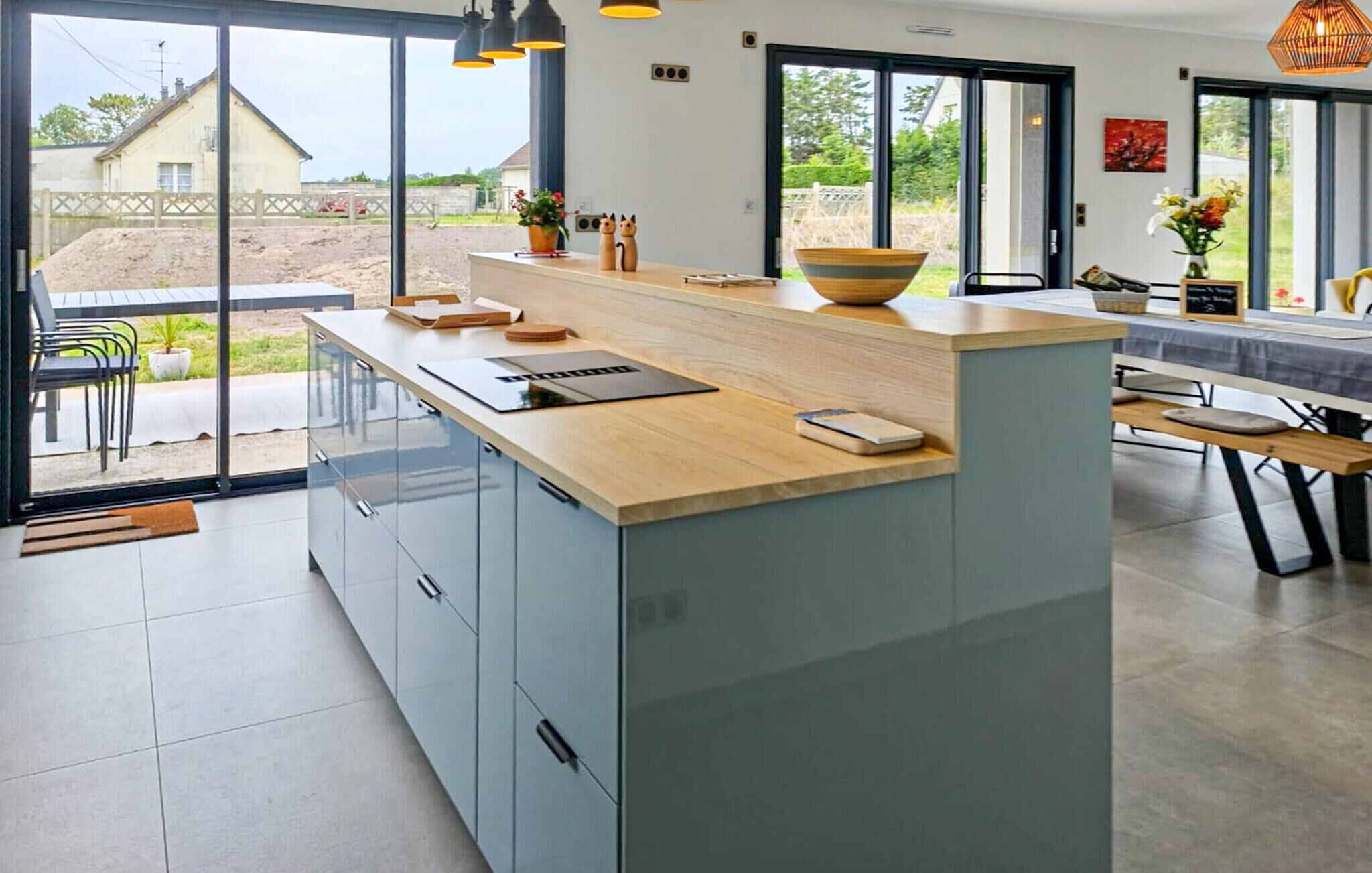 A modern kitchen with a large island, built-in appliances, and a view to the outside.
