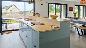 Una cocina moderna con una isla grande, electrodomésticos integrados y vistas al exterior.