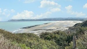 A coastal landscape with a sandy beach, rocky outcrops, and a clear blue sky. - Ancien moulin restauré (Clerques)