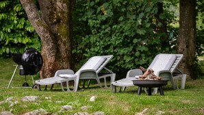 A grassy outdoor area with two lounge chairs and a barbecue grill. - Ancien moulin restauré (Clerques)