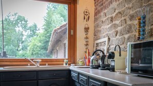 A kitchen with a large window, a brick wall, and a coffee machine. - Ancien moulin restauré (Clerques)