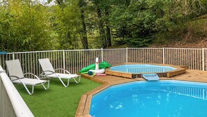 En trädgård med en pool, två solstolar och uppblåsbara poolleksaker.