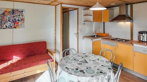Ett kompakt kök med ett matbord, en röd soffa och en tavla på väggen.