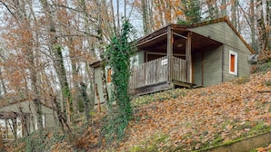 Un chalet rustique doté d’un porche en bois, entouré d’un feuillage automnal et d’arbres.