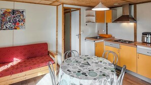 A compact kitchen with a dining table, a red sofa, and a painting on the wall.