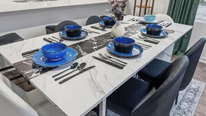 Ein moderner Essbereich mit einem Marmortisch, blau-schwarzem Geschirr und schwarzen Stühlen.
