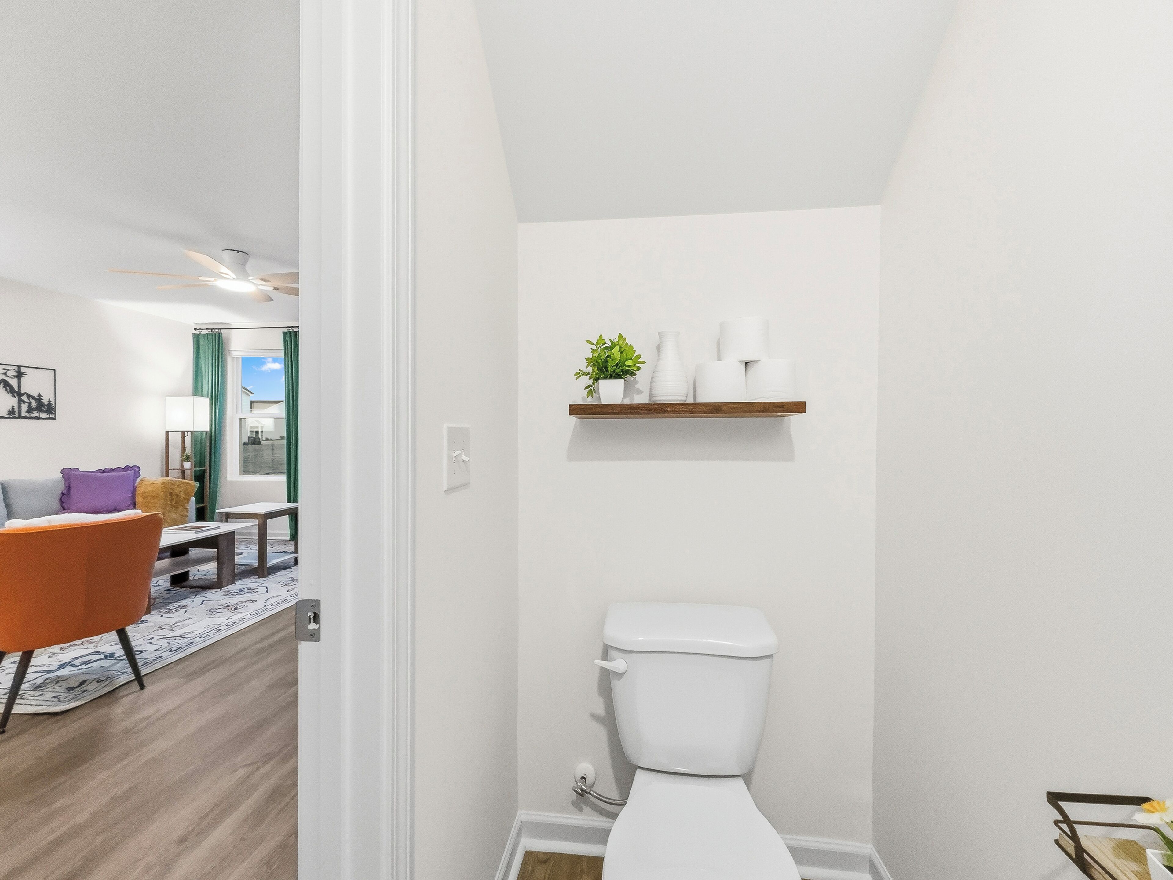 Un baño moderno con un inodoro, un estante con artículos de aseo y un ventanal.