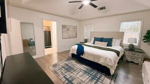 A bedroom with a bed, bedside tables, a ceiling fan, a window with blinds, and a door leading to a bathroom. - Spacious County Oasis near Tupelo (Saltillo)