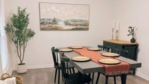 A dining area with a table set for four, surrounded by chairs, a potted plant, and a painting on the wall. - Spacious County Oasis near Tupelo (Saltillo)