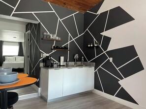 Et moderne køkken med hvide skabe, en granitbordplade og et geometrisk vægdesign.