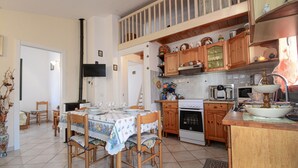 Una cocina con armarios de madera, estufa, microondas y una mesa de comedor con sillas.