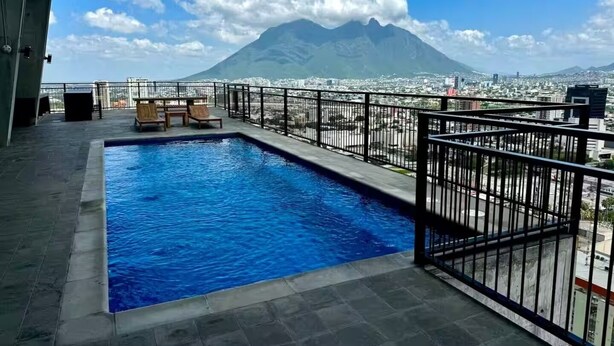 Piscina no terraço com vista para uma montanha e para a paisagem urbana.