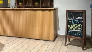 Uma receção com acabamento em madeira e uma placa de quadro negro a dizer 'Bem-vindo a Barrio'.