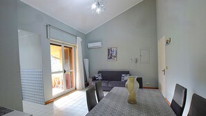 Uma sala de jantar com uma mesa posta para quatro pessoas, um sofá e uma cadeira.