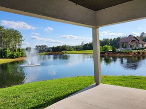 A covered outdoor area with a pond, a fountain, and a view of a house with a stone facade. - Great location in St John's County (St Johns)