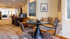 A hotel lobby with a round table, leather chairs, a sofa with cushions, a large framed picture, and a reception desk with a computer. - Ski in/Ski Out to Gondola,Hot Tubs,Pool, Ski Valet (Vail)
