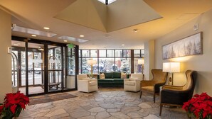 A lobby with a stone floor, a green sofa, and two armchairs. - Ski in/Ski Out to Gondola,Hot Tubs,Pool, Ski Valet (Vail)