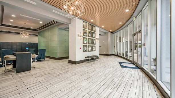Eine moderne Lobby mit gewölbter Decke, Holzvertäfelung, einer Rezeption, einer Sitzecke und großen Fenstern mit Blick.
