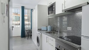 Een moderne keuken met een wasmachine, een magnetron en een spoelbak.
