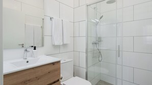 Een moderne badkamer met een douchecabine van glas, een witte wastafel en een houten wastafelmeubel.