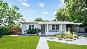 Een modern, gelijkvloers huis met een verzorgd gazon, een betonnen pad en een houten omheining.