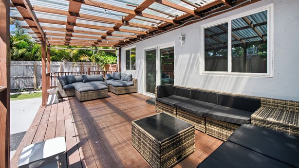 Een overdekt terras met rieten meubilair en een houten dek.
